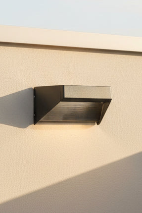 An LED up and down light fixture installed on a wall, with a matte black finish and a label indicating the brand and model details.