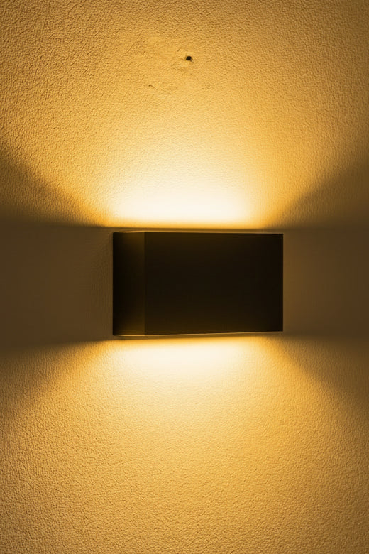 An LED up and down light in matte black with a label indicating the brand and model details, mounted on a wall.