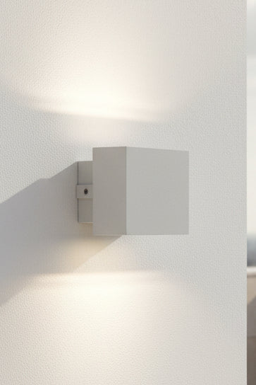 A matte white LUMAX brand up and down light with LED bulbs, model LX/114056, displayed against a warm-toned background.