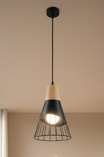 A pendant light with a black cage shade and wooden top, with a bright light bulb visible