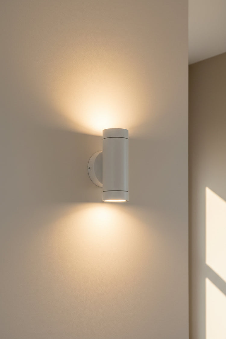 A white LUMAX wall washer light fixture mounted on an orange wall, displaying a bright white light.