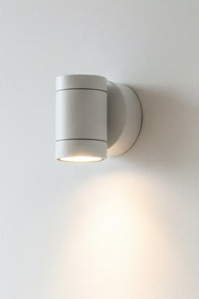 A white LUMAX wall washer light fixture mounted on a wall, illuminating a sign with the text 'LUMAX'.