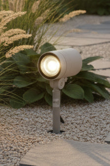 An outdoor spike light with a silver finish, branded by LUMAX, installed in grassy terrain.