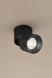 A black foldable LED downlight installed on a blue ceiling, with the light from the LED being visible.
